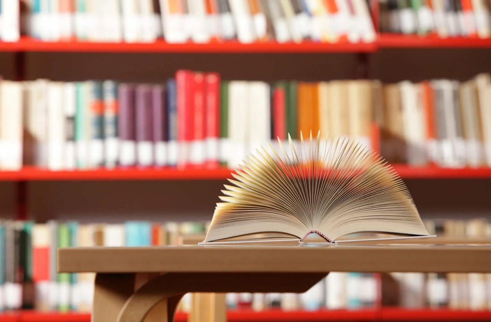 A book is open on the table in front of some books.