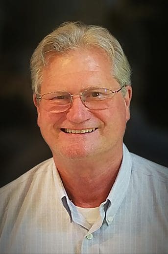 A man with glasses smiling for the camera.