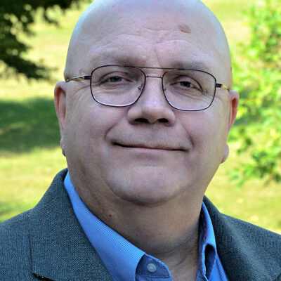 A man with glasses and a beard wearing a jacket