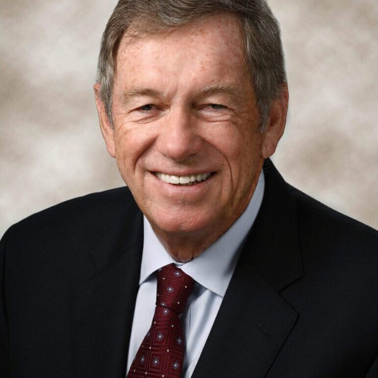 A man in suit and tie smiling for the camera.